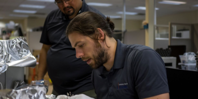 Alex Richards Director of Engineering wearing gloves working with scope parts