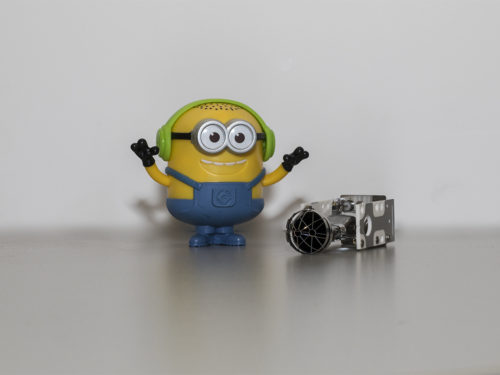 Minion with green headphones standing next to the CDEM instrument